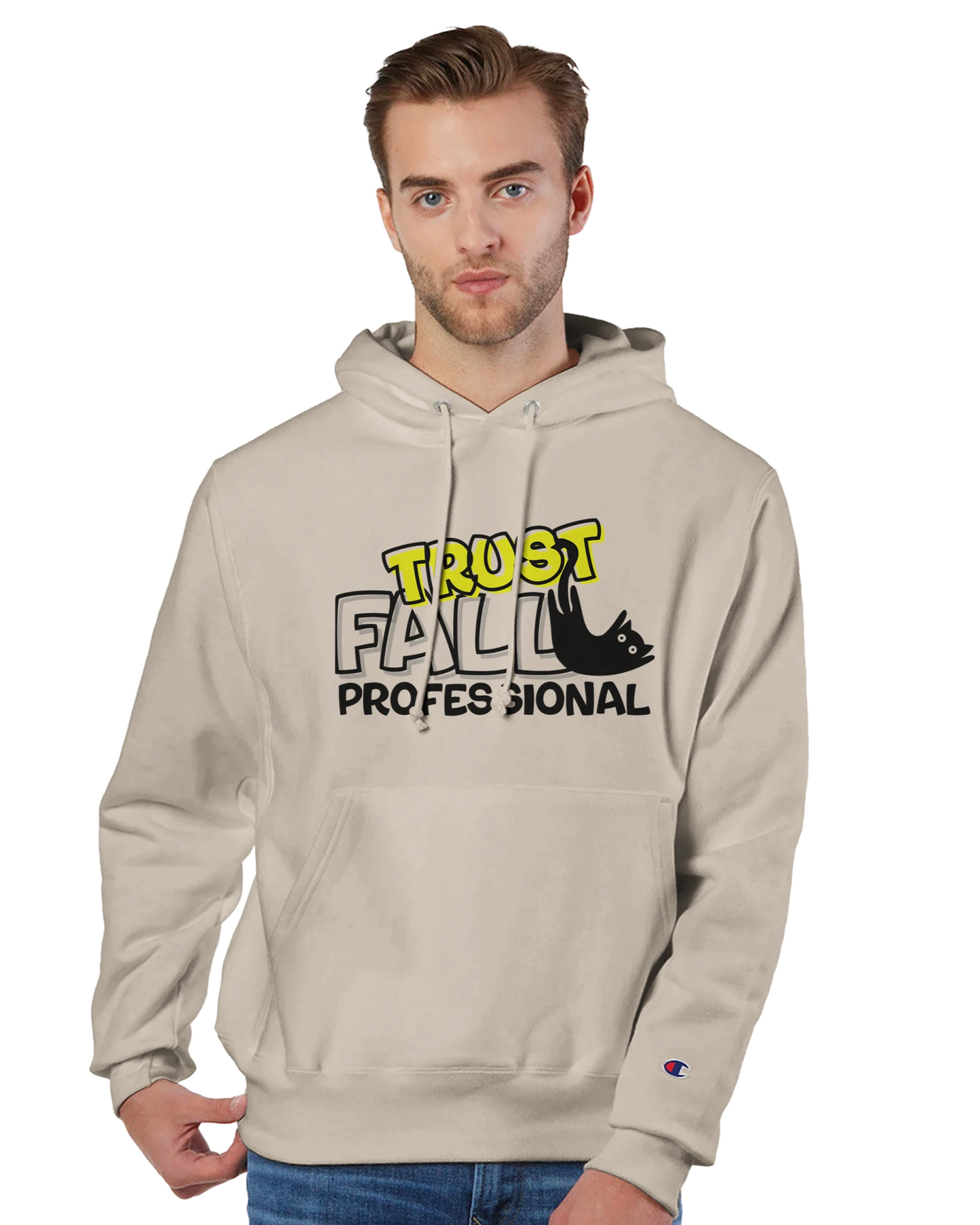 Model wearing a sand Champion pullover hoodie with the “Trust Fall Professional” graphic on the front, featuring bold yellow and black lettering and a falling cat illustration.