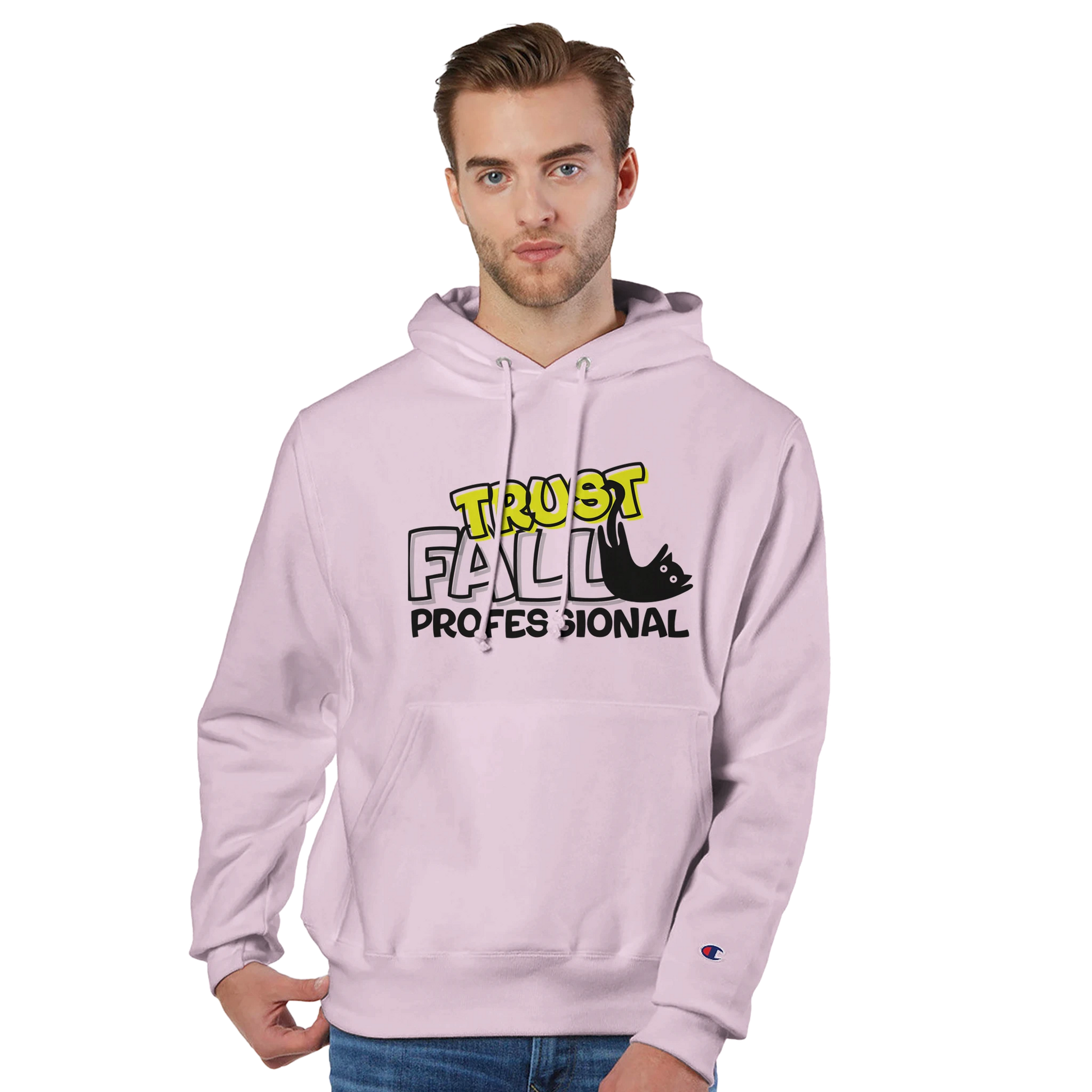 Model wearing a body blush Champion pullover hoodie with the “Trust Fall Professional” graphic on the front, featuring bold yellow and black lettering and a falling cat illustration.