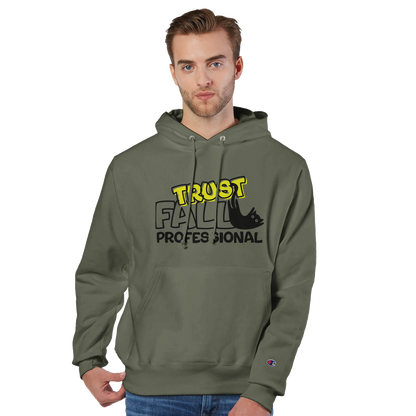 Model wearing a fresh olive Champion pullover hoodie with the “Trust Fall Professional” graphic on the front, featuring bold yellow and black lettering and a falling cat illustration.