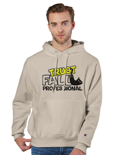 Model wearing a sand Champion pullover hoodie with the “Trust Fall Professional” graphic on the front, featuring bold yellow and black lettering and a falling cat illustration.