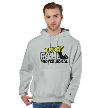 Model wearing a silver grey Champion pullover hoodie with the “Trust Fall Professional” graphic on the front, featuring bold yellow and black lettering and a falling cat illustration.