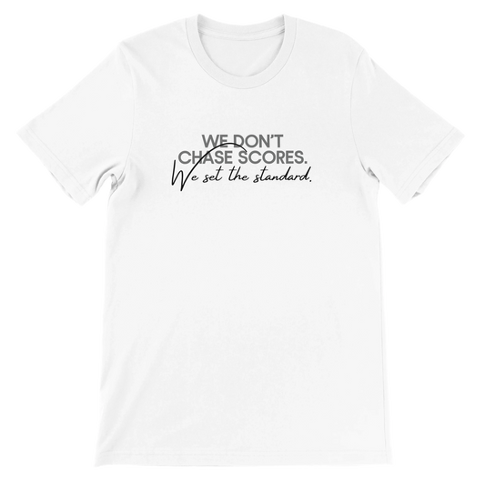 White unisex t-shirt with minimalist text design reading “We Don’t Chase Scores. We Set the Standard.” in gray and black font, part of the Sideline Authority Collection by Hit Zero Co.